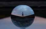 round glass ball reflecting man standing