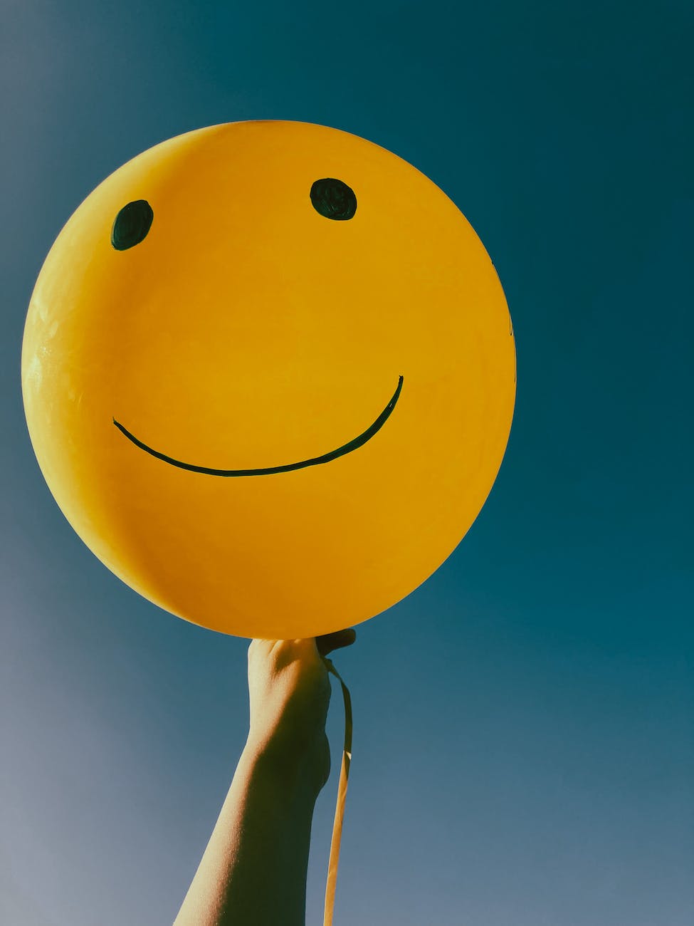 close up shot of a person holding a yellow balloon